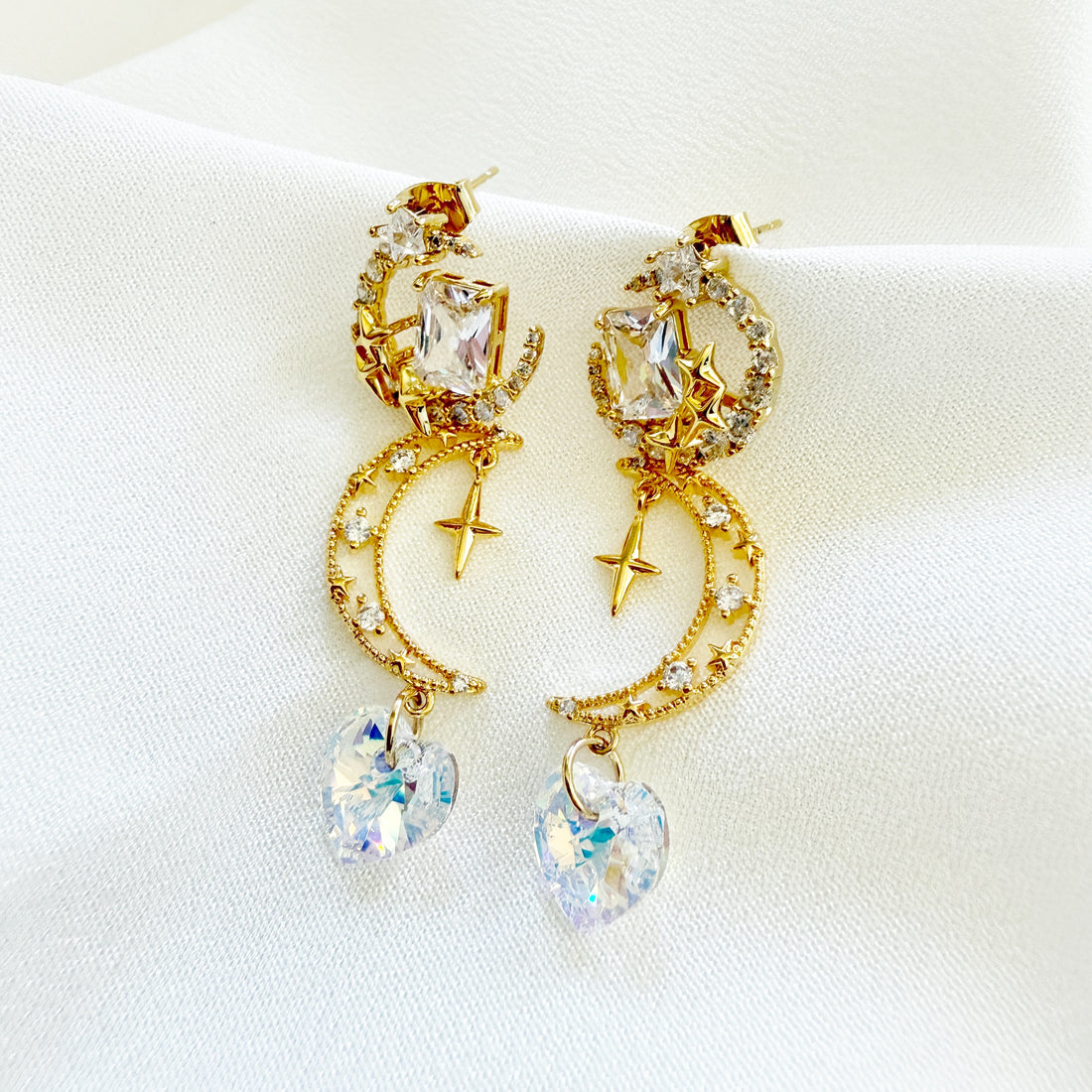 A pair of gold dangle earrings crafted with 14k gold plated brass in celestial crescent moon and shooting star designs highlighted by sparkly cubic zirconia swarovski crystals heart shaped drops. An unique jewelry gift for wedding, prom, party and celebrations