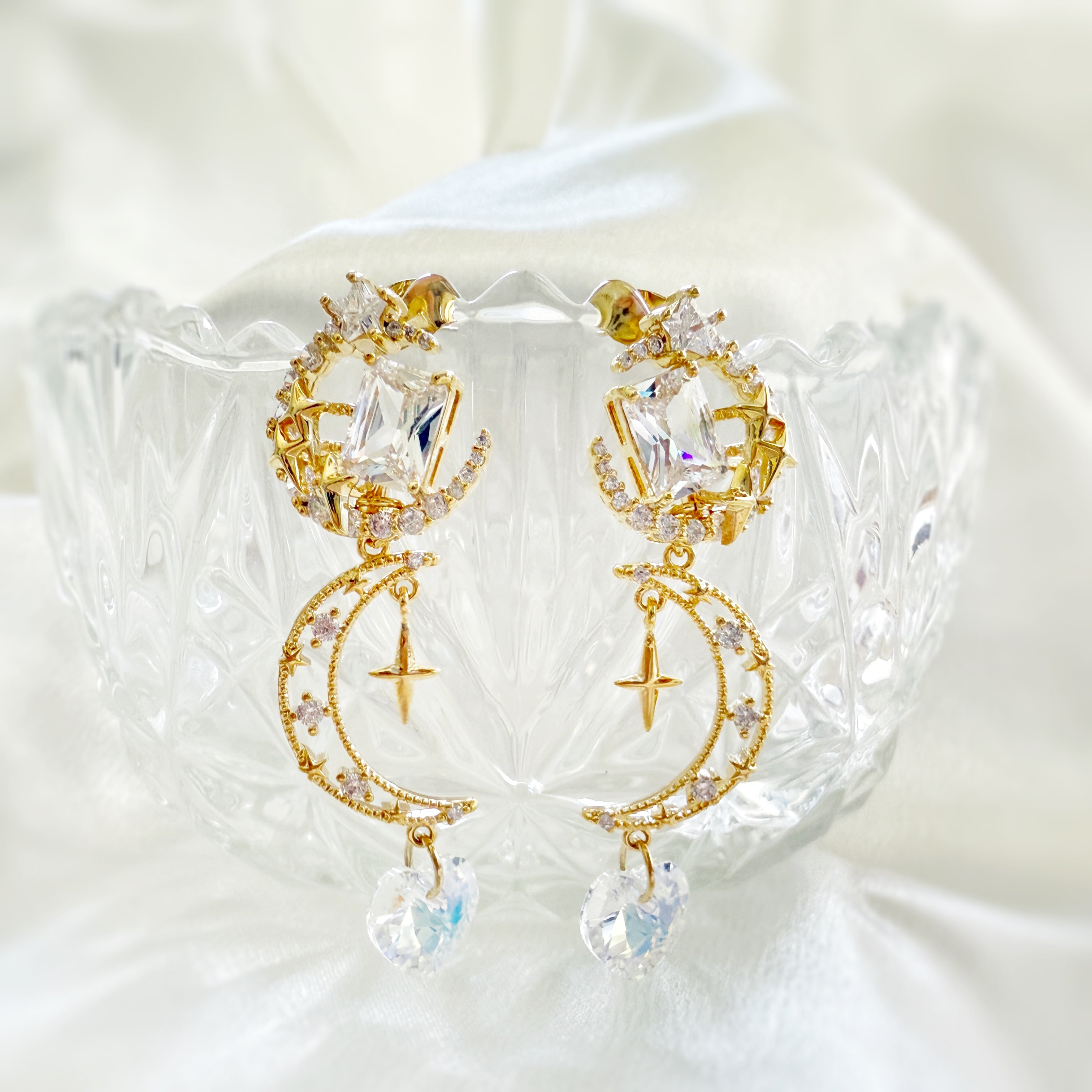 A pair of gold dangle earrings crafted with 14k gold plated brass in celestial crescent moon and shooting star designs highlighted by sparkly cubic zirconia swarovski crystals heart shaped drops. An unique jewelry gift for wedding, prom, party and celebrations