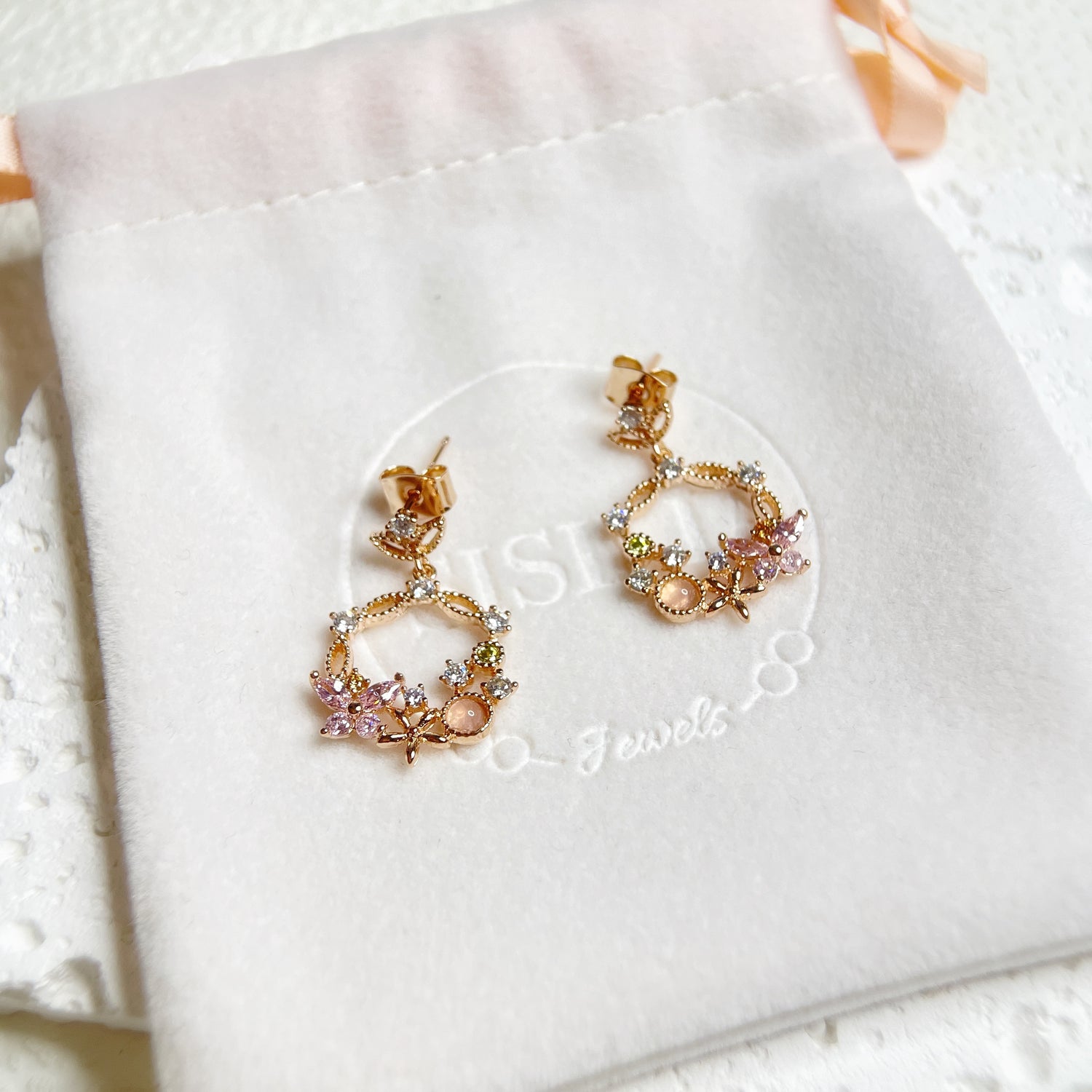 Rose gold butterfly and flower design drop earrings crafted with sparkle multi colored stones on a branded jewelry bag  - Sisilia Jewels