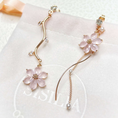 Rose gold mismatched earring dangles  in six petals pink flower hanging on rose gold flower stems on a jewelry bag - Sisilia Jewels