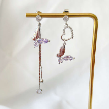 Pair of mismatched earring dangles in dream butterfly design crafted with semi-precious purple and colorless swarovski crystals, as well as a silver heart shape drops and two tassels drops - Sisilia Jewels