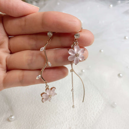 Dangling earrings in six petals pink flower hanging on rose gold flower stems holding by hands - Sisilia Jewels