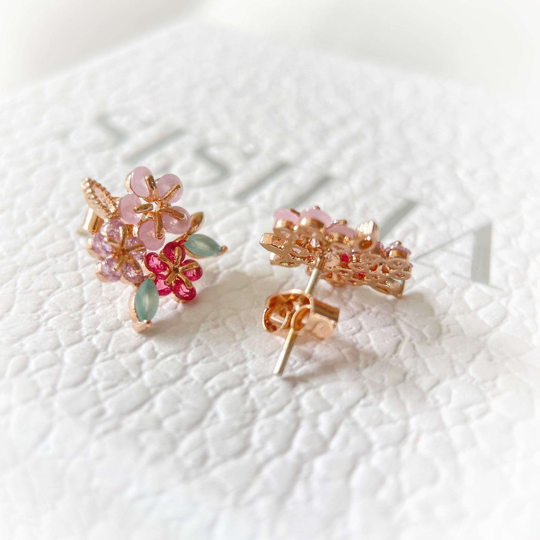 Pair of triple cluster flower earrings studs design in pink, mint green and red, highlighted by rose gold colour  leaves with push back earring pin closure on a gift box-  Sisilia Jewels