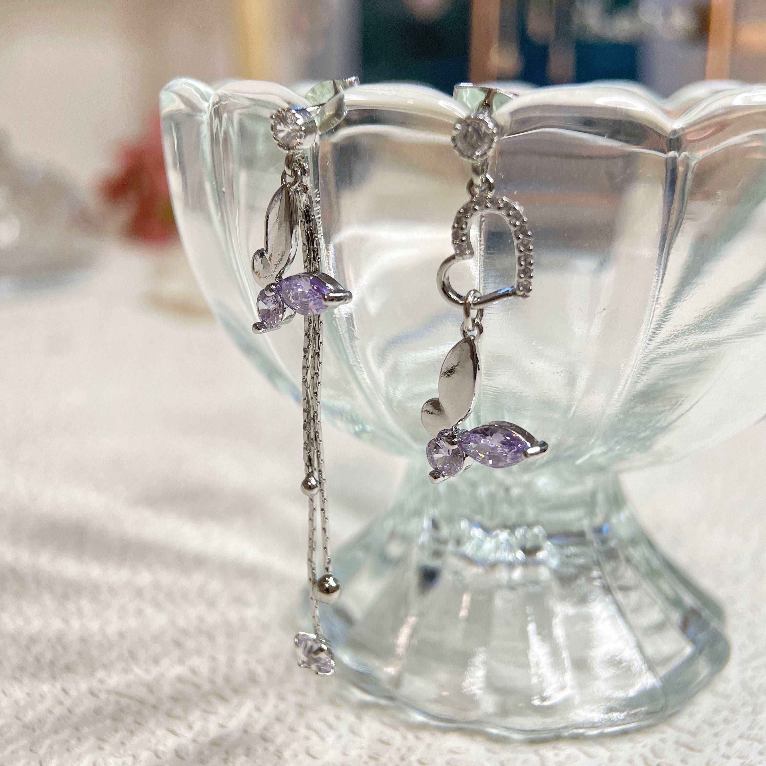 Pair of mismatched earring dangles in dream butterfly design crafted with semi-precious purple and colorless swarovski crystals, as well as a silver heart shape drops and two tassels drops - Sisilia Jewels